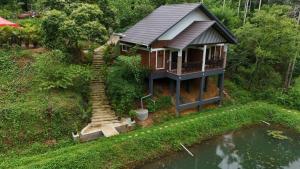 a small house with stairs next to a body of water at Casta Wild Resort in Batheri