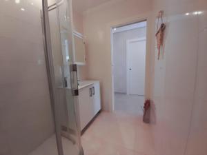 a bathroom with a glass shower and a kitchen at Coqueto apartamento con parking in Laredo +9 photos