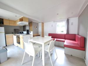 a living room with a red couch and a table and chairs at HARMONIE Mobil home au cœur d'un camping 5 étoiles in Lit-et-Mixe