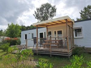 a mobile home with a deck with a pergola at HARMONIE Mobil home au cœur d'un camping 5 étoiles in Lit-et-Mixe