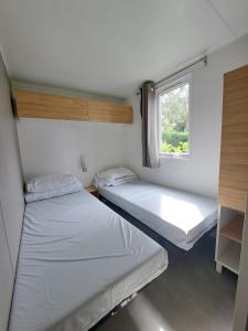 two beds in a small room with a window at HARMONIE Mobil home au cœur d'un camping 5 étoiles in Lit-et-Mixe