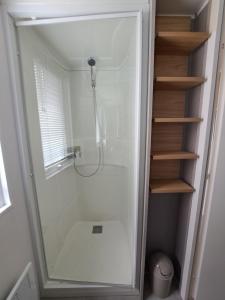 a shower with a glass door in a bathroom at HARMONIE Mobil home au cœur d'un camping 5 étoiles in Lit-et-Mixe