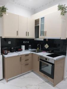 a kitchen with white cabinets and a stove top oven at Loutraki comfortable apartment center 50m from the sea in Loutraki