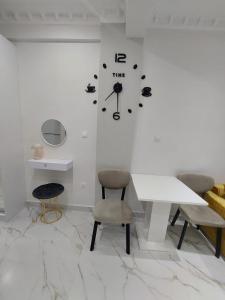 a white room with a table and a clock on the wall at Loutraki comfortable apartment center 50m from the sea in Loutraki +2 photos