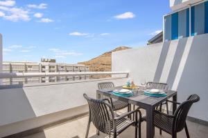 a table and chairs on a balcony with a view at Patalavaca Beach, One Bedroom Apartment in Patalavaca