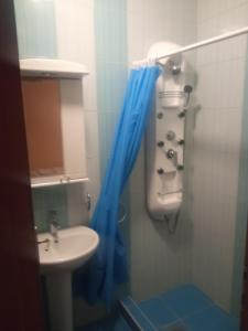 a bathroom with a sink and a blue shower curtain at Apartmani Igalo Nada i Vile in Igalo