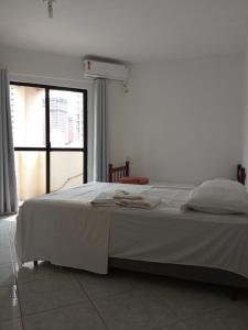 a white bed in a room with a window at Residencial Maravilha in Perequê
