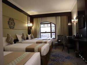 a hotel room with three beds and a desk at Al Mukhtara Plaza Hotel - فندق المختارة بلازا in Medina