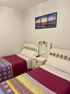 a bedroom with two beds and a picture on the wall at Hospedaje Angelica in Santillana del Mar