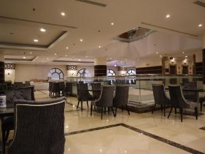 a restaurant with tables and chairs and a bar at Al Mukhtara Plaza Hotel - فندق المختارة بلازا in Medina