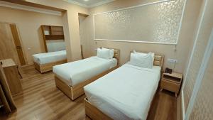 a small room with two beds and a mirror at Hotel Bankir Khiva in Khiva