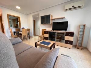 Una sala de estar con un sofá y un televisor de pantalla plana. en ACV - Costa Azahar II-2ª linea planta 6 norte 2, en Oropesa del Mar