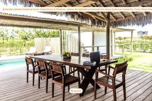a wooden table with chairs and a laptop on a deck at Casa Pipa em condomínio de luxo no Fortim in Barra (2)