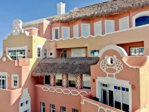 a pink building with a thatch roof at Casa Tortugas Boutique Hotel - A Hidden Gem in Cancun in Cancún +53 photos
