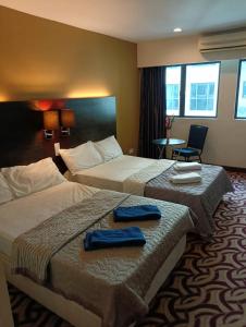 two beds in a hotel room with towels on them at Sky Saffron 3 Beds Kk city centre in Kota Kinabalu