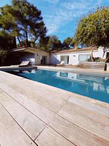 una piscina con terraza de madera junto a una casa en villa Bikini Bormes les mimosas, en Bormes-les-Mimosas