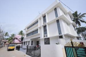 a white building with a car parked in front of it at INDIGO Springs in Trivandrum