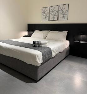 a bedroom with a large bed with white sheets at Black Swan Villa in Al Ḩadd +14 photos