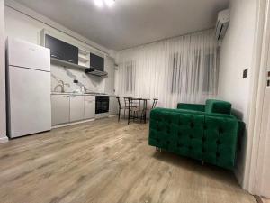 a living room with a green couch and a kitchen at Vily Apartment in Focşani