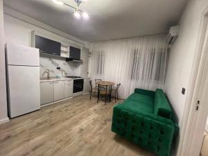 a living room with a green couch and a kitchen at Vily Apartment in Focşani +7 photos