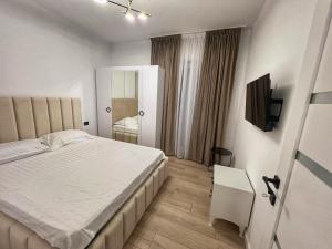 a bedroom with a white bed and a television at Vily Apartment in Focşani