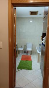 La salle de bains est pourvue de toilettes et d'un tapis vert. dans l'établissement Retiro da Magnólia, à Sobrosa