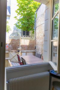 balkon ze stołem i krzesłami oraz oknem w obiekcie La Dodolela w mieście Chinon