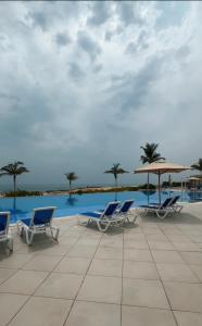 a group of chairs and umbrellas next to a swimming pool at Naseem AlBahar in Muscat
