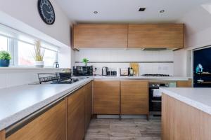 a kitchen with wooden cabinets and a clock on the wall at Luxury City Stay Coop Live & Etihad with Free Parking in Manchester