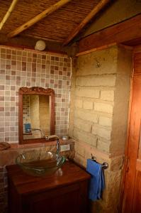 uma casa de banho com um lavatório de vidro e um espelho. em Mawasi Finca em Villa de Leyva
