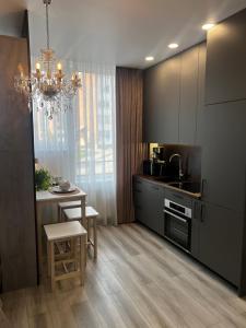a kitchen with a chandelier and a kitchen with a table at Chic Residence apartament 2 in Šiauliai