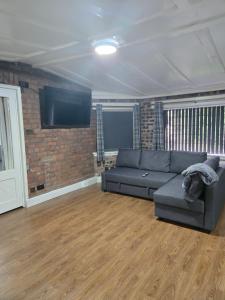 a living room with a couch and a brick wall at Rainsough Cottage Guest House - Sleeps upto 8 with ensuite - Free Parking & WiFi in Manchester