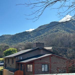 ein kleines Haus mit einem Berg im Hintergrund in der Unterkunft Encantos del Valle - Santa Rosa de Calamuchita in Santa Rosa de Calamuchita
