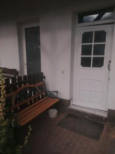 una panca di legno seduta di fronte a una porta bianca di Ferienwohnung Dolecki Rippach a Lützen