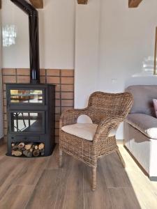 a wicker chair in a living room with a fireplace at La Palmera Casa Rural in L'Aldea