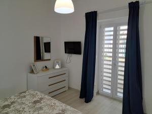 a bedroom with blue curtains and a bed and a television at Casa Vacanze Argento in Bacoli
