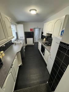 a kitchen with white cabinets and a black floor at Luna Apartments Newcastle Gateshead 1 in Gateshead