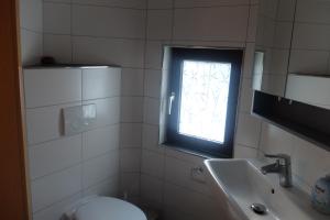 a bathroom with a toilet and a sink and a window at Ferienwohnung Jehn in Fulda