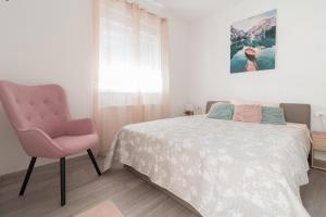a bedroom with a bed and a pink chair at Villa Nicolle in Privlaka +23 photos