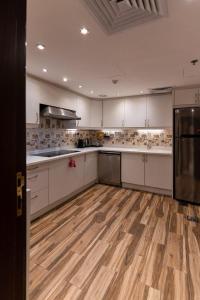 a large kitchen with white cabinets and wooden floors at جناح خاص في أجنحة طيبة in Al Madinah