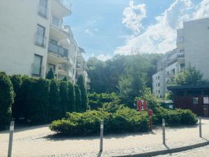a courtyard with bushes and a building and a red phone booth at Pohulanka Old City - parking & balcony in Gdańsk
