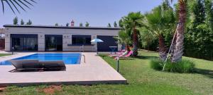 a house with a swimming pool and palm trees at Domaine Farah in Meknès