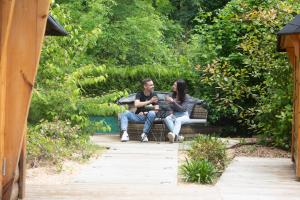 a man and woman sitting on a bench in a garden at La Bulle de Chantilly - Spa & sauna privatifs & petit déjeuner gourmand in Saint-Leu-dʼEsserent