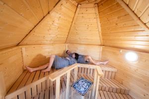 two people laying in a wooden igloo in a wooden room at La Bulle de Chantilly - Spa & sauna privatifs & petit déjeuner gourmand in Saint-Leu-dʼEsserent +1 photo