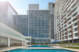 een zwembad in het midden van twee hoge gebouwen bij Noble Resort Hotel Melaka in Melaka