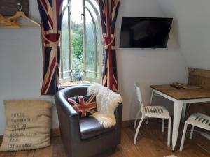 a living room with a chair and a television at Quaint Studio Loft Room nr Hampton Court in Thames Ditton