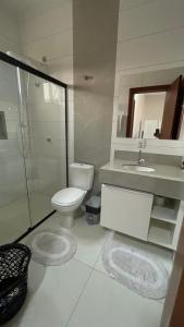 a bathroom with a toilet and a sink and a shower at Madeira Loft - Apartamento Centro in Juína