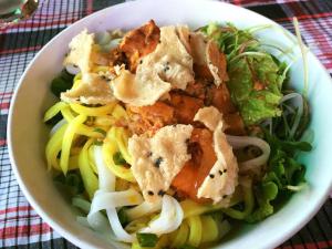 a white bowl of food with noodles and greens at Bonsai Villa Hoi An in Hoi An