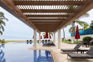 a pool with chairs and umbrellas next to the ocean at Luxury Beach Front 3Br Condo in Cruz de Huanacaxtle