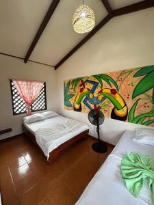 a bedroom with two beds and a painting on the wall at Miss Miriam BeachFront Cabins in Tortuguero